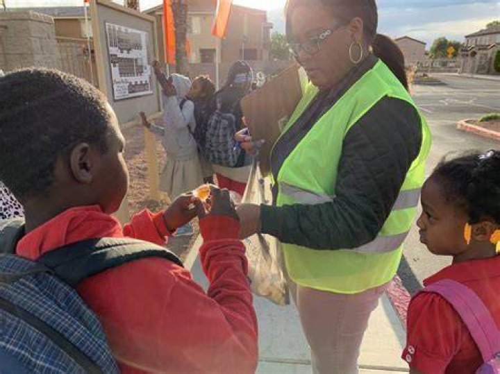 Elease Johnson hands out lollipops to students before their walk to