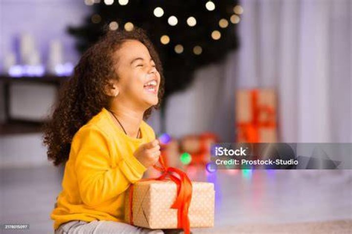Excited african girl laughing with Christmas gift, empty space | Image: Unsplash
