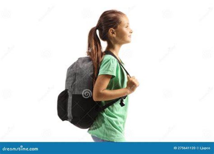 girl carrying a brown backpack while looking at a castle in Agra, India
