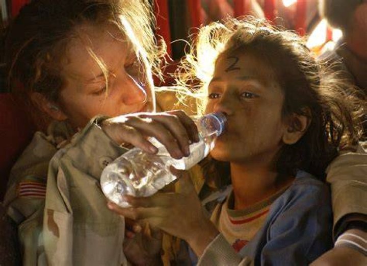 Humanitarian aid woman giving water to a refugee child