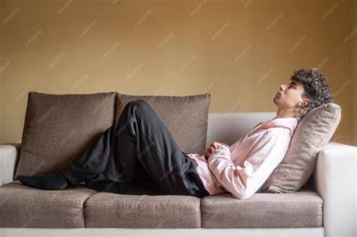 person lying on sofa with book covering face