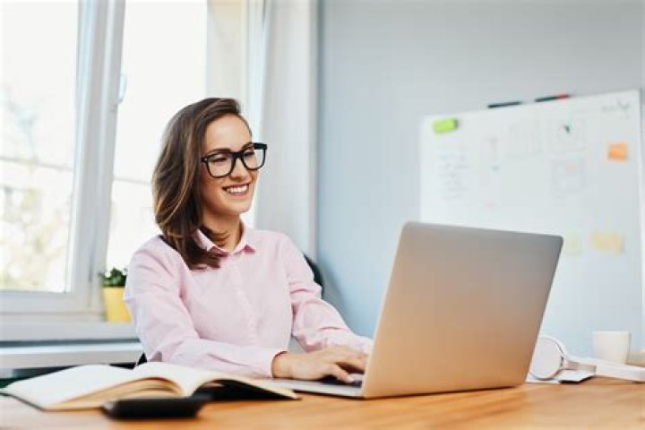 smiling woman working on laptop in cafe