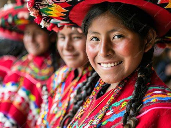 Three indigenous Peruvians smiling with their llama